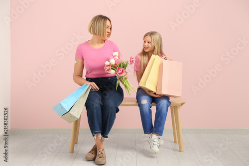 Beautiful young woman with bouquet of tulips and her cute little daughter hol...