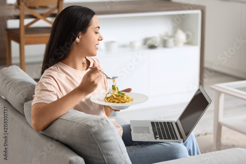 Young woman with laptop eat...