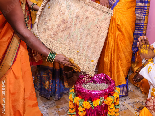 Traditional Indian Hindu Wedding Ritual Pouring Sacred Rice from a woven bamboo winnowing basket (chaat, suupa)