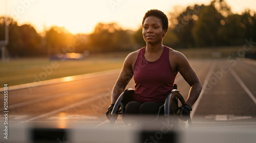 Woman in wheelchair on running track at sunset