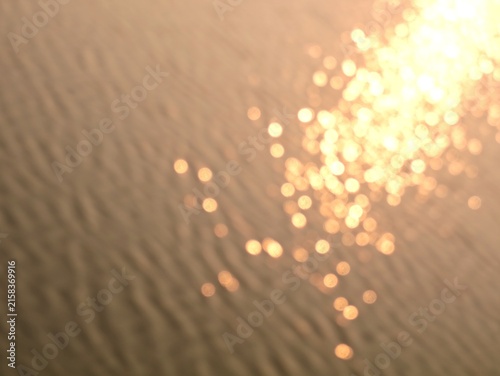 Fotografie Abstract warm golden blurred of sunlight reflecting on water surface, creating shimmering bokeh lights