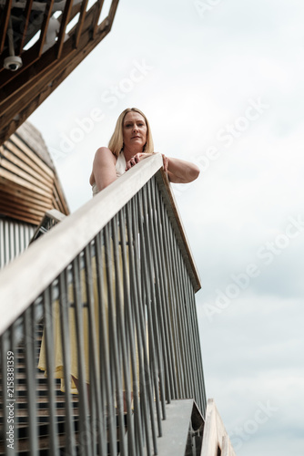 Bild auf Leinwand Woman leaning on railing looking upward contemplating