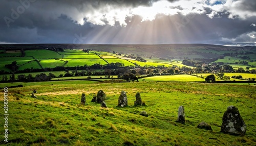 Sunlight breaking through stormy clouds over ancient standing stones and green rolling hills.
