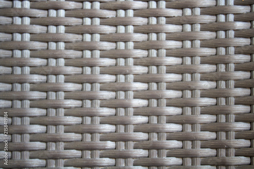 Woven Rattan Wicker Texture Close-Up of Outdoor Furniture Seat Pattern in Neutral Gray Brown Tones.