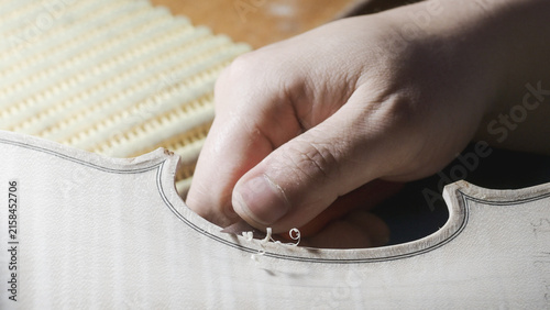 Fotografie Close up of luthier's hand carefully carving the f hole of a violin, demonstrati