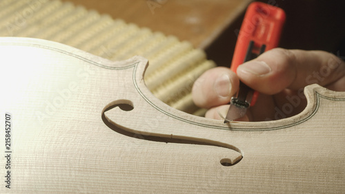 Fotografie Skilled luthier carefully trimming violin f hole edge, demonstrating meticulous