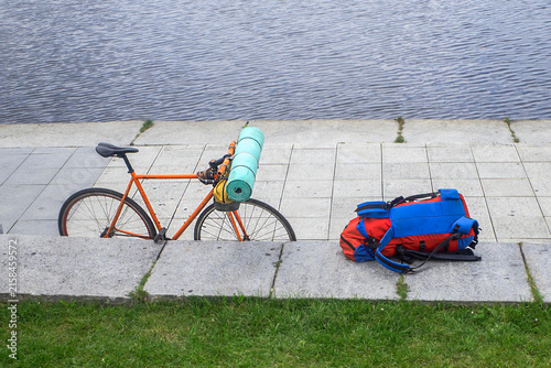 A bicycle and a backpack on the embankment on a summer day
