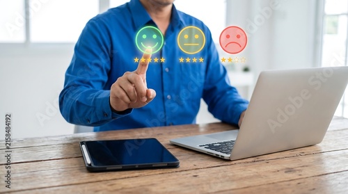 Customer experience concept, businessman choosing a happy emoticon with five stars on a virtual screen to rate service