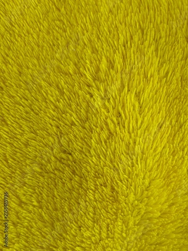 Macro close-up shot of vibrant yellow plush fabric texture, featuring soft fluffy microfiber fleece material for abstract background design.