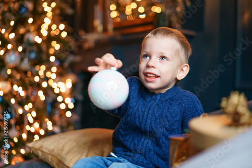 Canvas Print Excited caucasian child laughs while dangling a pastel christmas ball on a strin