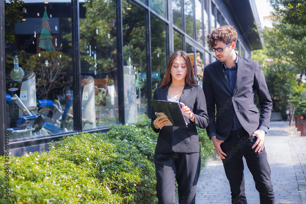 Fototapeta premium Business colleagues reviewing documents on tablet while walking outside office building