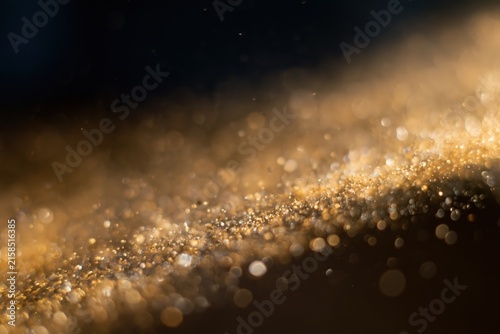 The Golden Dust Particles in Soft Bokeh Across a Diagonal Dark Background