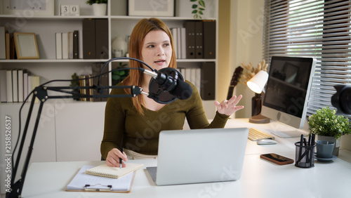 Fotografía Young female podcaster speaking into a microphone while recording at home