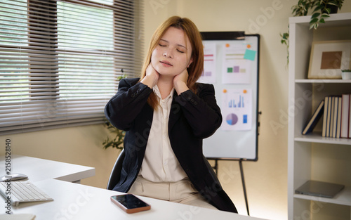 Fotografie Young businesswoman easing neck pain after prolonged computer work