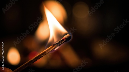 Burning matchstick flame close up against dark background