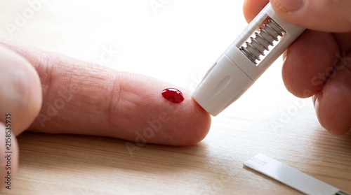 Person checking blood glucose level with a lancet device for diabetes management test