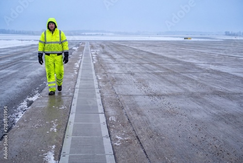 Ground Staff Member Walking Across Snowy Airport Apron During Winter Operations