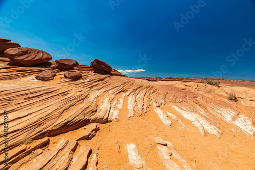 Layered Sandstone and Boulders in an Arid Desert Under a Deep Blue Sky