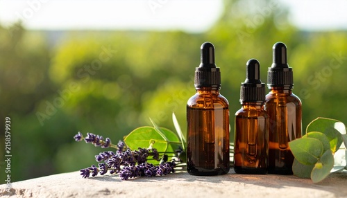 Glass bottles with dropper caps and lavender on stone.
