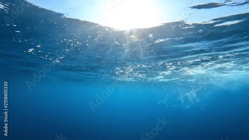 Underwater ocean surface shines brightly as sunlight penetrates through clear blue water.