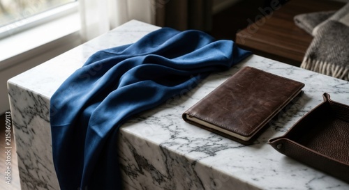Luxurious Blue Silk Fabric Draped on a Marble Surface Beside a Leather Journal