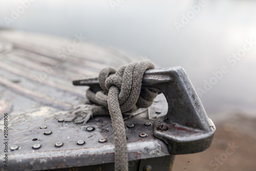 Bild auf Leinwand Close-up view of a weathered metal cleat with a rope knot secured tightly, situa