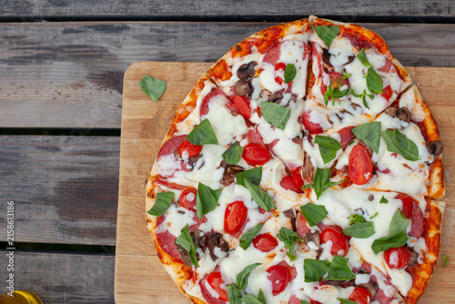 Foto Freshly baked pizza features mozzarella cheese, cherry tomatoes, black olives, a