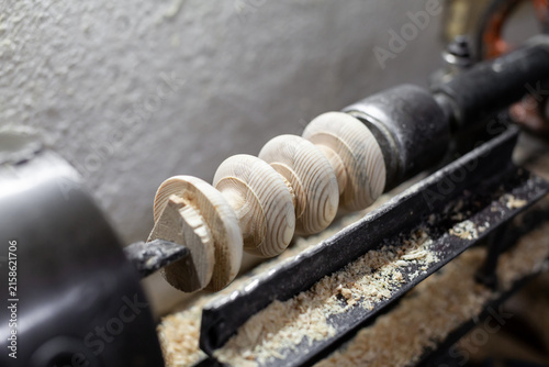 Cuadro en lienzo Wooden spools are being crafted on a lathe in a workshop, with wood shavings and
