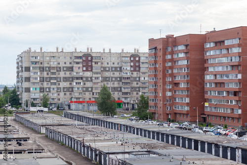 Quadro su tela Residential apartment buildings stand alongside garages and a parking area, with
