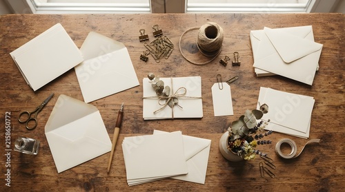 Flat lay of stationery with envelopes, blank cards, twine, and dried flowers on wood