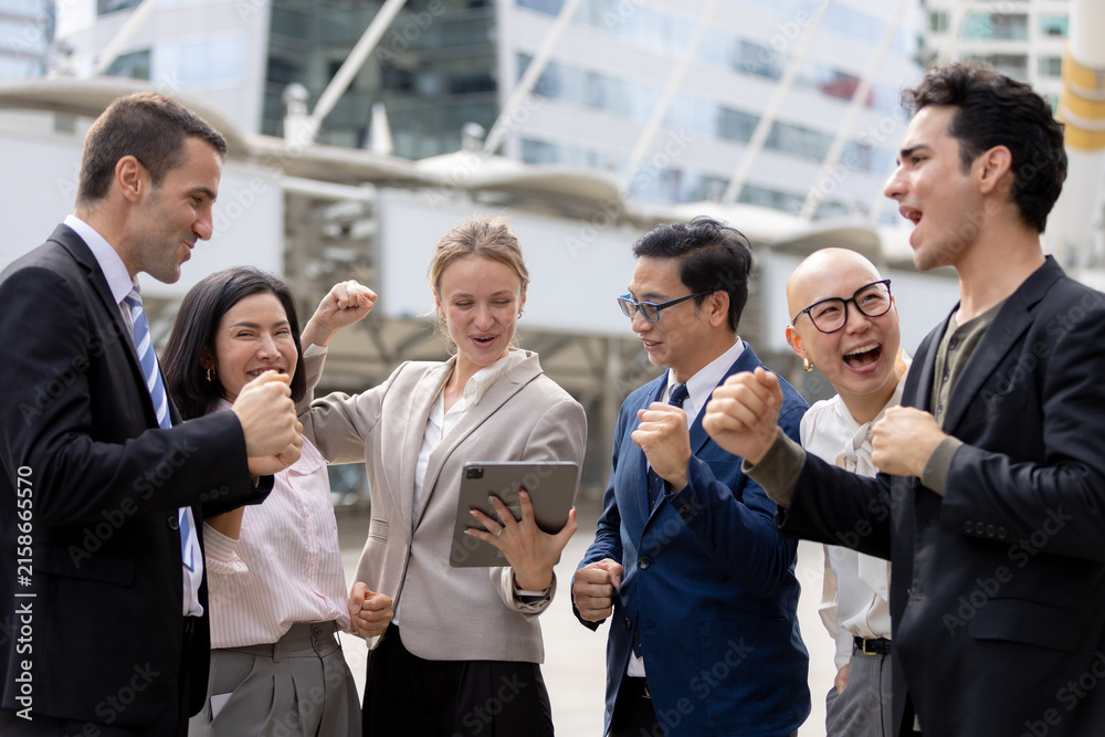 Obraz premium Diverse business professionals celebrating success outdoors with raised fists, showing teamwork, achievement, corporate victory, motivation, collaboration and positive team spirit.