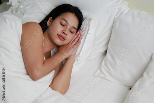 Foto Young woman sleeping peacefully in white bed sheets, finding comfort and deep re