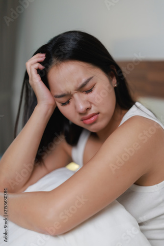 Obraz na plátne Young woman experiencing intense headache or migraine in bed, suffering from dis