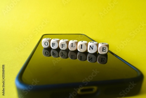 Canvas Print The word OFFLINE spelled out with small wooden blocks on a blank smartphone screen over a bright yellow background, representing a digital detox