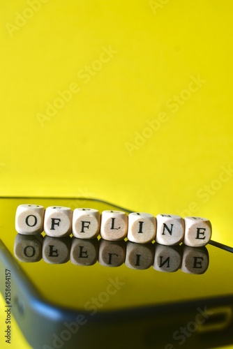 Cuadro en lienzo The word OFFLINE spelled out with small wooden blocks on a blank smartphone screen over a bright yellow background, representing a digital detox