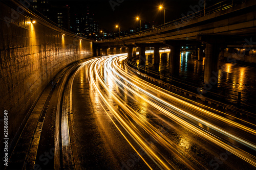 Принти на полотні Long exposure photograph capturing golden car light trails on a curved highway