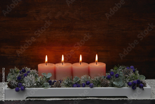 Vierter Advent: Dekoratives Adventsgesteck mit rosa Kerzen, Eukalyptuszweigen und Beeren.