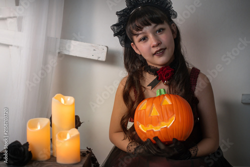 Girl is holding a Halloween pumpkin lantern towards the camera. selective focus