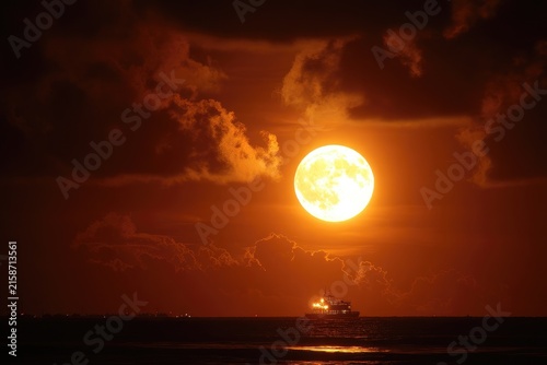 Full, orange moon over dark sea