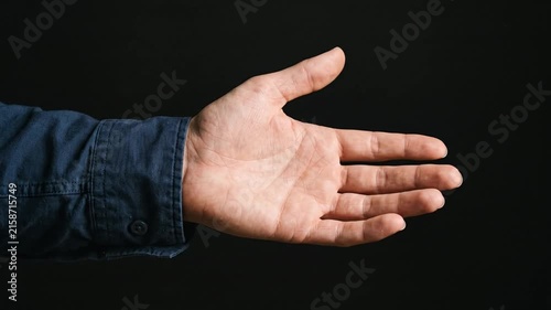 Adult human hand opening and closing against a solid dark background
