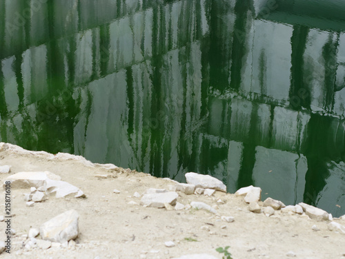 wall of marble blocks reflecting in a lake in the Cava Valsora area in the province of Carrara