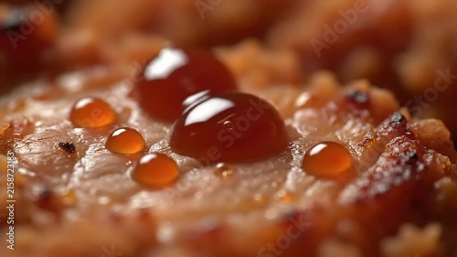 Close-up macro shot of glistening honey drops slowly drizzling over a golden crispy fried piece of savory seasoned meat surface texture