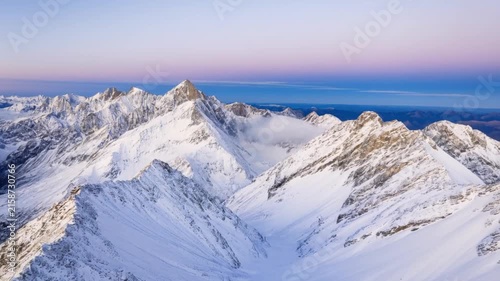 Breathtaking panoramic view of a vast snow-capped mountain range under a beautiful clear sky at sunrise or sunset