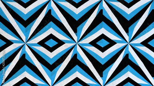 Dynamic repeating geometric pattern featuring bold black, white, and vibrant blue shapes, creating an optical illusion with interconnected rhombuses and radiating chevron designs, ideal for