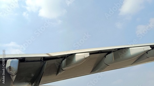 Close-up photo of an aircraft wing taken from below with the canoe fairing and flaps under blue sky