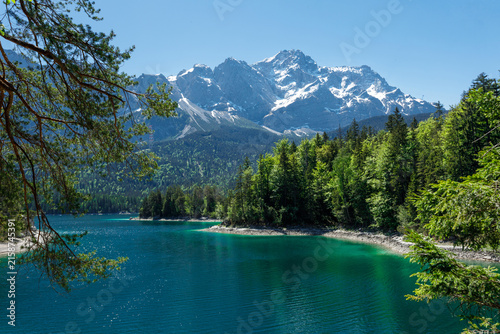 Travel landscape of Zugspitze Alps in Bavaria, Germany, scenic summer nature panorama with forest, Eibsee lake, snow mountains peak. Alpine landscape