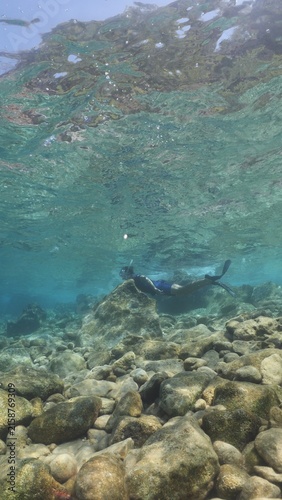 young man free dives  underwater with sun beams and rays