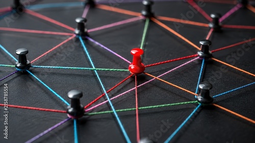 Business network with colorful strings connecting push pins on a dark board, representing communication, teamwork, relationships, organization and strategic connections.