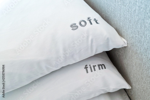 Close-up on firm and soft pillow alternatives placed on bed for hotel room guests to choose in accordance to preference for a comfortable sleep