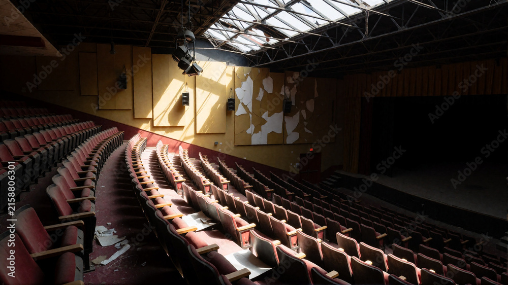 Naklejka premium Abandoned theater interior with empty red seats and peeling walls
